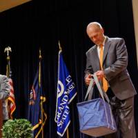 Dr. Len O'Kelly speaking at the podium and Dr. Jeffrey Potteiger holding the People's Choice Winner swag bag.